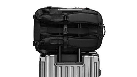 Airbag Lite carry-on backpack resting on top of a wheeled suitcase