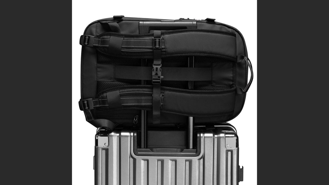 Airbag Lite carry-on backpack resting on a wheeled suitcase at the airport