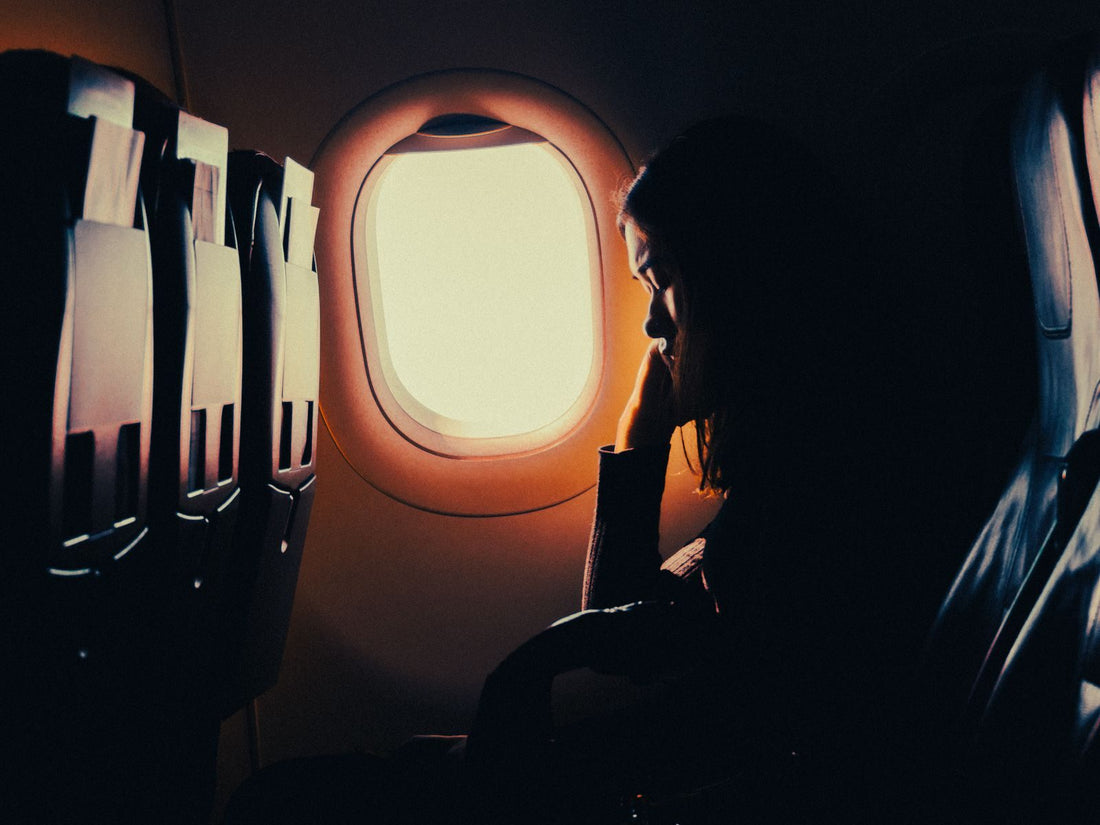 Silhouette of a passenger resting by an aircraft window seat on a long flight
