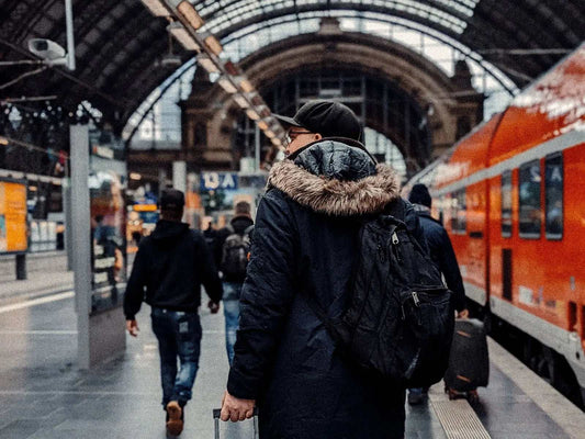 Traveller with a backpack walking along a platform at Frankfurt main station beside a red regional train